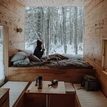 person sitting in a tiny home in a forest in the winter